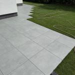 Helle graue Feinsteinzeugplatten auf einer großzügigen Terrasse mit direktem Übergang zum sattgrünen Rasen – professionelle Ausführung durch Garten- und Landschaftsbau Bublica in Düsseldorf