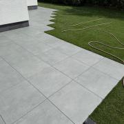 Helle graue Feinsteinzeugplatten auf einer großzügigen Terrasse mit direktem Übergang zum sattgrünen Rasen – professionelle Ausführung durch Garten- und Landschaftsbau Bublica in Düsseldorf